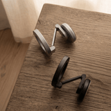 Silver and black Magneto wall mounts folded on wooden table, showing heavy-duty metal articulating arm construction.