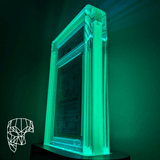 Phantom Display ghost edition, glow-in-the-dark graded card display case, positioned at an angle, showing the premium crystal-clear acrylic design with vivid green illumination.