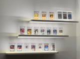 Phantom Display acrylic cases showcasing a collection of PSA-graded Pokémon and sports cards on illuminated shelves, featuring 99.6% UV protection for premium preservation.