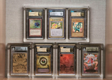 Display of high-grade Magic: The Gathering, Pokémon, and Yu-Gi-Oh! cards, including Black Lotus, Pikachu Illustrator, and Blue-Eyes White Dragon, protected in premium Phantom Display cases with CGC and Beckett grades.