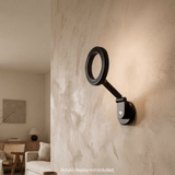 The Magneto articulating wall mount installed on a textured wall, showing the minimalist black ring design without a card.