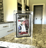 One Piece collectible card displayed in a crystal-clear Phantom x Slabmags acrylic display case on a kitchen countertop.